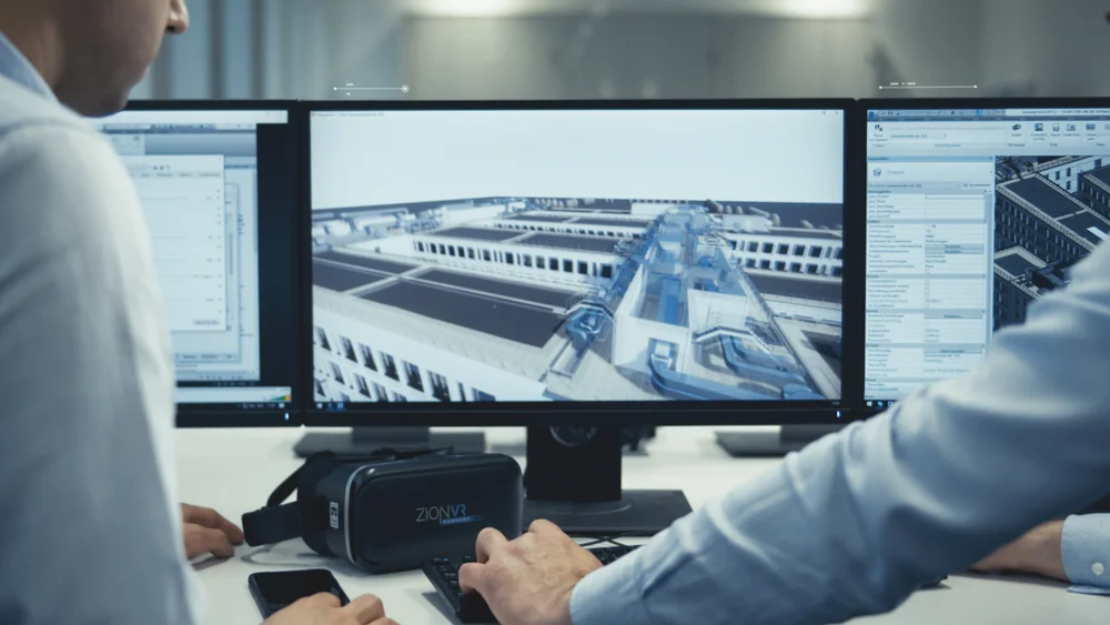 Bild zeigt 2 MĂ€nner vor einem Computer. Sie schauen auf den Bildschirm.