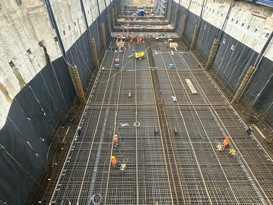 Bewehrungsarbeiten für die Betonage der Tunnelsohle beim Bau des Südschnellwegs in Hannover. Die tief gegründete Baugrube zeigt die vorbereitete Stahlbewehrung für den zukünftigen Straßentunnel, während mehrere Fachkräfte die Arbeiten auf der Tunnelsohle ausführen.