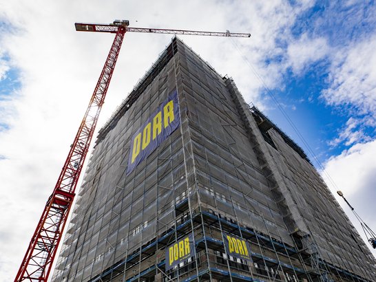 Eingerüstetes Hochhaus im Rohbau mit Turmdrehkran während der Fassadenarbeiten auf einer Baustelle in Berlin.