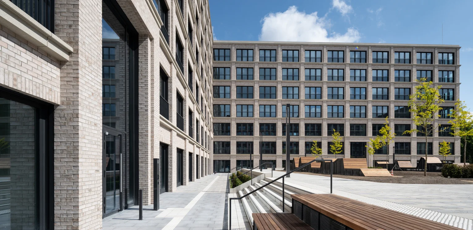 TechnoCampus, Berlin Detailed view of the 2 new buildings of the TechnoCampus; you can see a small stone staircase with a few steps leading to the green area; on the upper step are wooden benches; on the left is the facade of the building