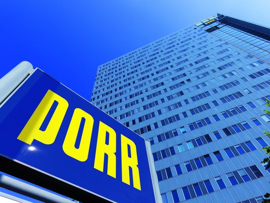 Blick von unten auf das Hochhaus der Firma PORR mit PORR Schild davor