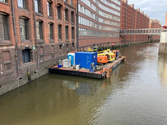 Arbeitsponton mit Baumaschinen und Baustelleneinrichtung bei der Sanierung einer Kaimauer an einem Fleet in Hamburg.