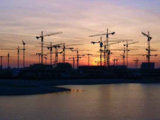 A picture of a sunset. There are cranes in the background.