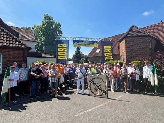 Gruppenfoto. Viele Menschen stehen unter einem PORR Schild. In dder Mitte steht ein Mann mit einer Fahne 