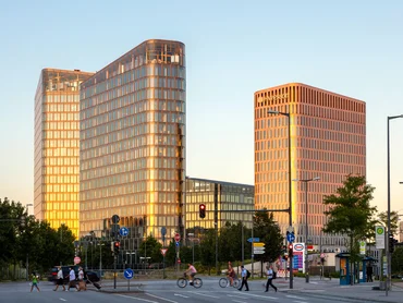 Blick auf die beiden HochhĂ€user des Hotelturms; Links sieht man den Blue Tower der ein BĂŒrogebĂ€ude ist; rechts sieht man ein Hotel, welches zur Marke Hyperion gehört; auffallend ist die raumhohe und bodentiefe Verglasung der Fenster; Bild bei Sonnenaufgang.