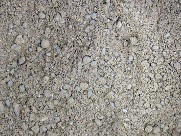 Foto: fein gemahlenes, dunkles, grünlich-graues Steinmehl mit vereinzelt gröberen Körnern flach aufgestreut