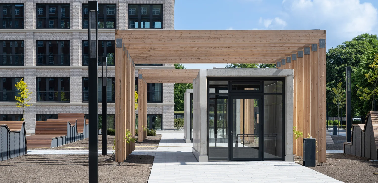TechnoCampus, Berlin Entrance to the underground car park; you can see the wooden carport that serves as the roof of the entrance; on the left you can still see parts of the benches; in the background is the building; in front of the entrance is a black rubbish bin;