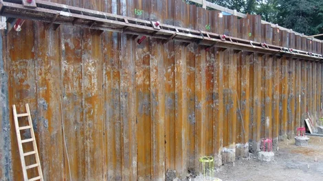 Bild einer Baugrube mit Spundwand; eine Leiter lehnt links im Bild