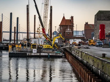 Bild zeigt die Kaimauer in Hamburg; auf einem Panton vor der Hafenmauer steht ein Spezialtiefbaugerät