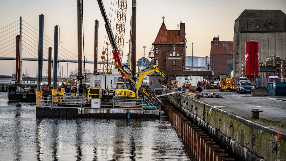 Bild zeigt die Kaimauer in Hamburg; auf einem Panton vor der Hafenmauer steht ein Spezialtiefbaugerät