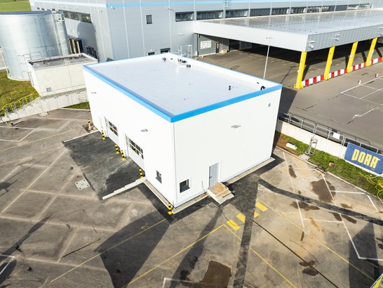 The image shows the workshop hall in Rammstein. The façade is white with a blue stripe on the roof.