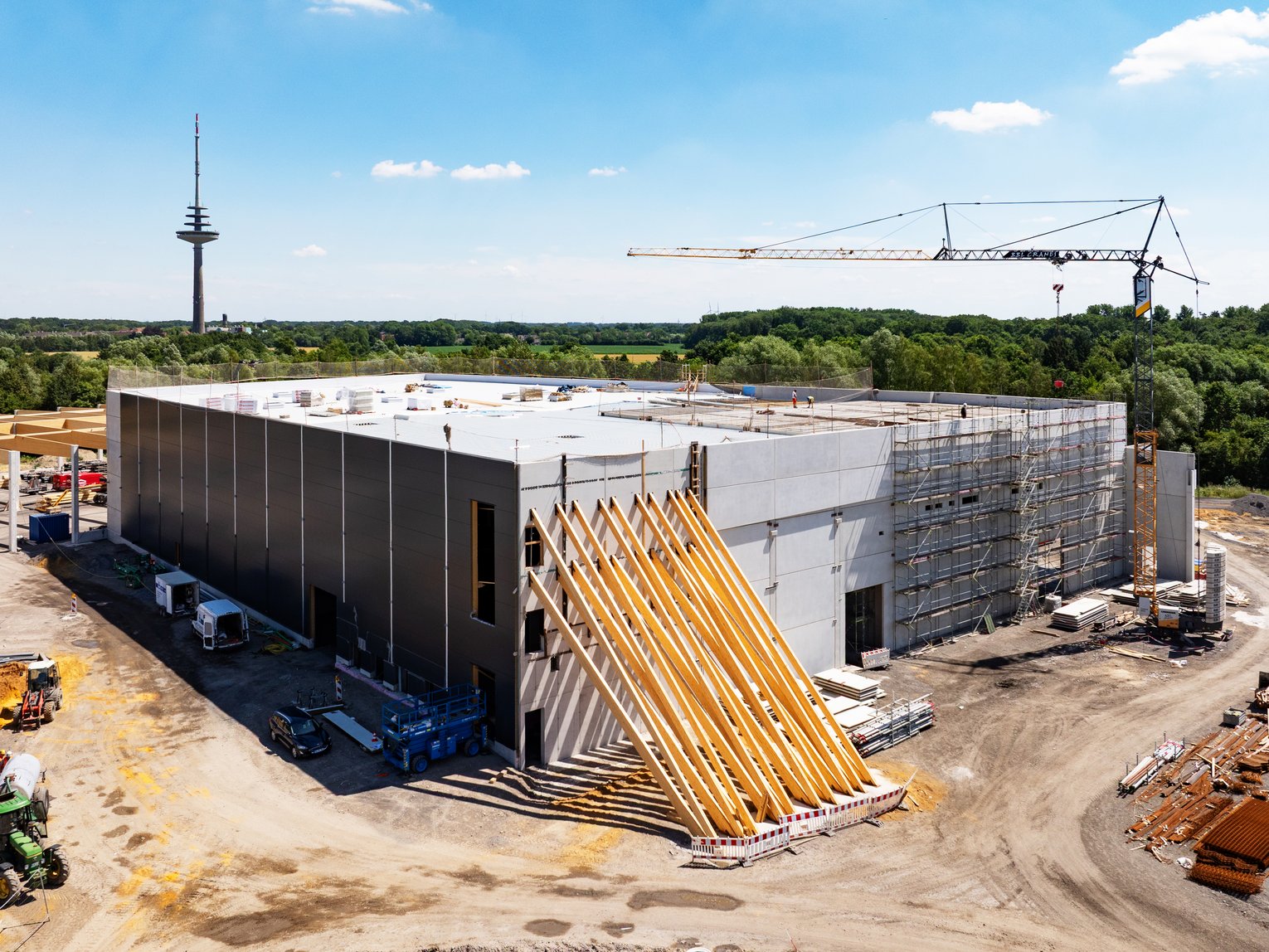 Construction of a new logistics and industrial building in Münster, involving the use of a crane, prefabricated elements and a timber structural framework during the building phase.